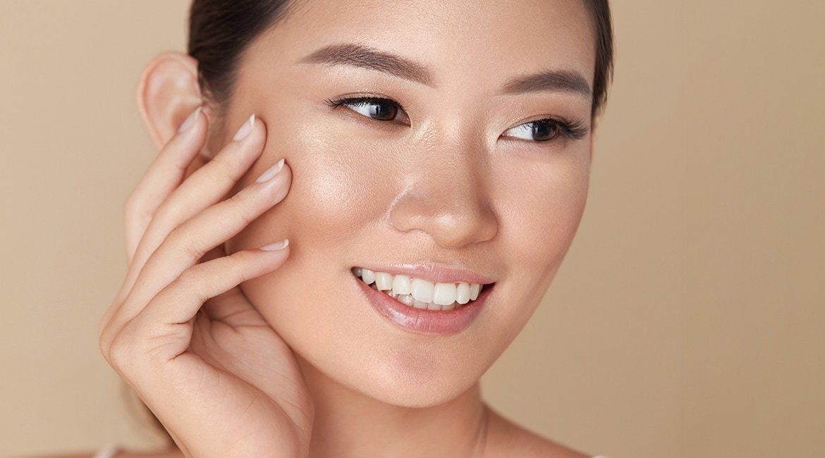 Eine junge Frau streicht sich über ihre rechte Wange